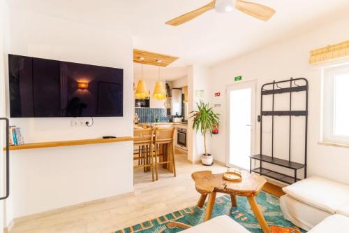 a living room with a couch and a tv on a wall at Casa Phoebe - NEW Renovated Burgau Apartment Sleeps 5 - Beach 1 min in Burgau