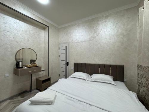 a bedroom with a large white bed and a mirror at Art Home in Tashkent