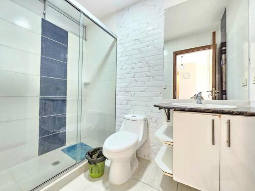a bathroom with a toilet and a glass shower at En el corazón de Santa Cruz, Departamento de un dormitorio in Santa Cruz de la Sierra