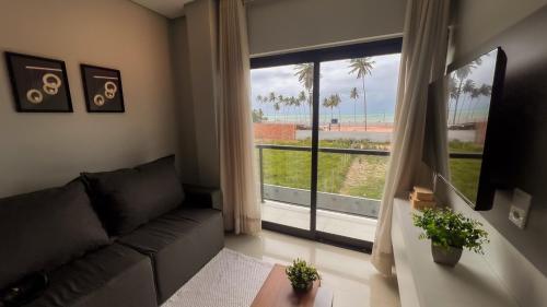 ein Wohnzimmer mit Couch und großem Fenster in der Unterkunft Apto Vista Mar 2 Suítes Piscina Japaratinga in São Bento