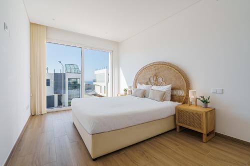 a white bedroom with a large bed and a large window at Antica Villa, luxury villa near the beach in Ribamar