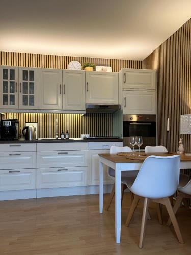 レーアにあるFerienwohnung Altstadt Perle_ 15164の白いキャビネットとテーブルと椅子のあるキッチン