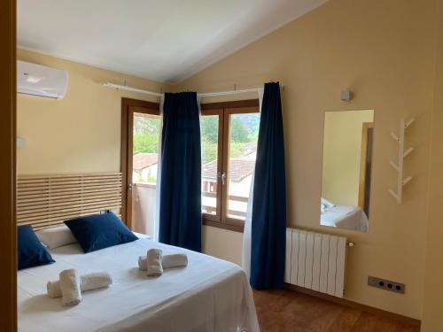 a bedroom with a bed with blue curtains and a window at Apartamento Casa Maru in Santillán