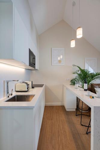 a white kitchen with a sink and a table at Ponto Alto Hotel in Lisbon