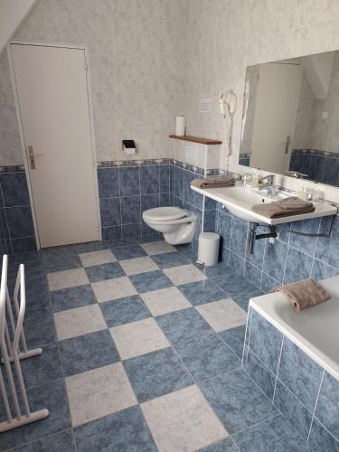 a blue tiled bathroom with a toilet and a sink at Manoir Du Stang in La Forêt-Fouesnant