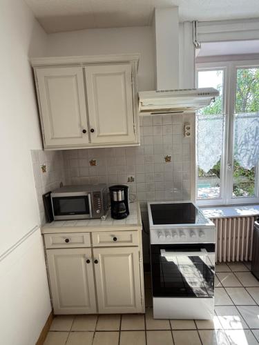 eine Küche mit weißen Schränken und einer Mikrowelle in der Unterkunft Chambres individuelles dans maison familiale in Vierzon