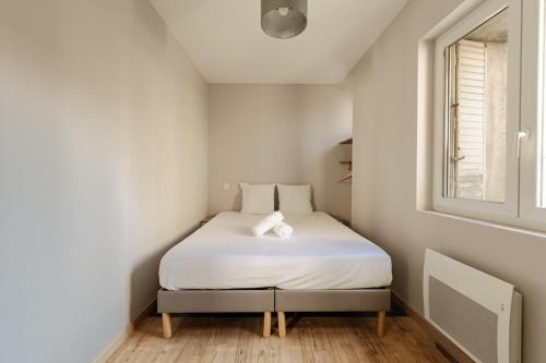 a small bedroom with a white bed with a window at Le Derby in Valence