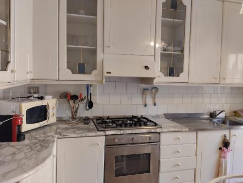 Una cocina con gabinetes blancos y un horno de estufa. en Amarcorde Home in Corso Buenos Aires con 6 posti letto, en Chiavari
