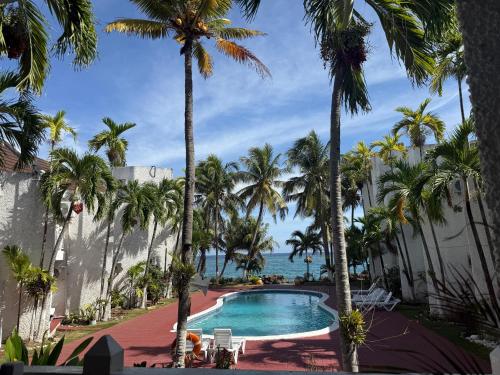 a pool with palm trees and the ocean at Beachfront home near Dunns River Falls in Tower Isle