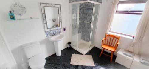 a white bathroom with a sink and a shower at Blue Door Apartment Main St, Carrigart, F92HC04 in Carrigart