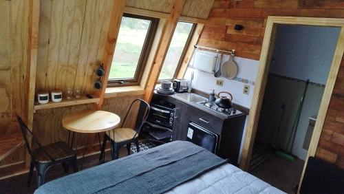 a bedroom with a kitchen with a stove and a table at Tiny Home El descanso del Pescador in Puerto Cisnes