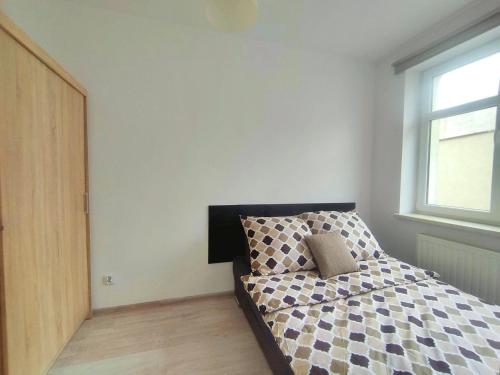 a bedroom with a bed with a black and white comforter at Sunny Stay by Grafit in Legnica