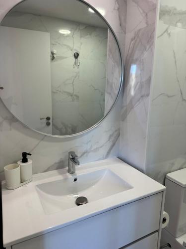 Un baño blanco con lavabo y espejo. en Pachi Beach Atlantic Garden Corralejo, en Corralejo