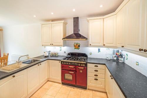 a kitchen with white cabinets and a red stove top oven at Central to town, 4 bedrooms, sleeps 8, parking for 4 plus cars in Stratford-upon-Avon