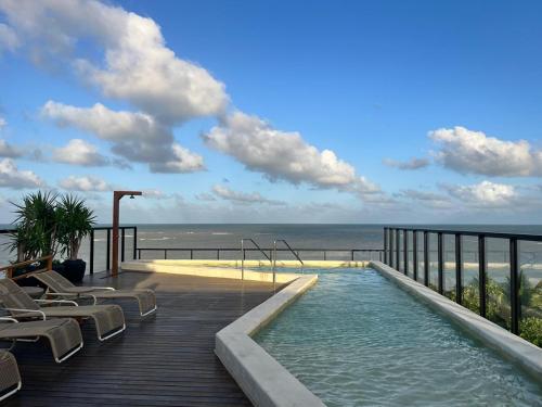 a swimming pool on a deck with a view of the ocean at Luxuoso Flat pé na areia no Restinga in João Pessoa
