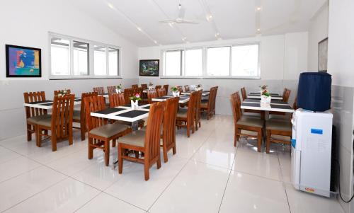 a dining room with tables and chairs and a refrigerator at Parkwood Elite in Bengaluru