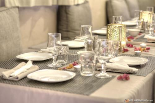 una mesa con platos blancos y vasos. en Guest House Bagdad Café, en Aït Ben Haddou