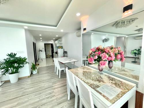 ein Raum mit weißen Tischen und rosa Blumen in der Unterkunft Pearl Nha Trang Beach Apartment in Nha Trang