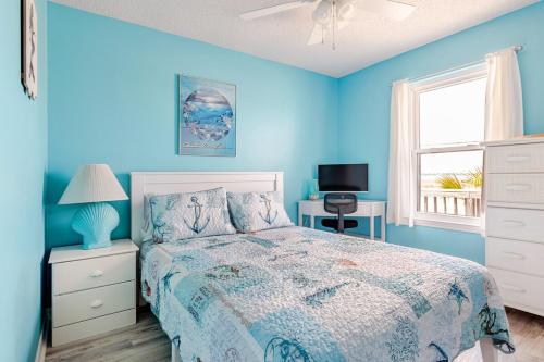 ein blaues Schlafzimmer mit einem Bett und einem Fenster in der Unterkunft Kokomo Key on Navarre Beach - Private Pool in Navarre