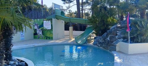 Una pequeña piscina con un tobogán en un parque infantil. en Mobilhome - La Palmyre Camping, en La Palmyre