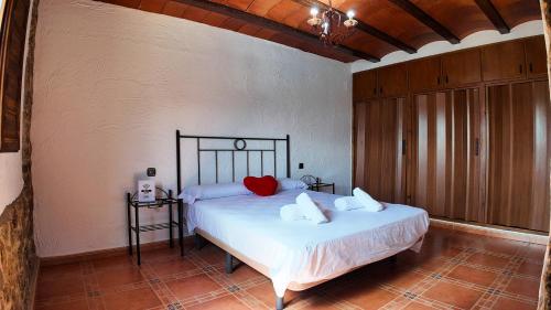 a bedroom with a bed with white sheets and red pillows at Ruralux Campo San Juan II in Moratalla