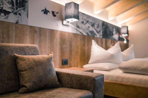 a room with a couch and a bed with pillows at Hotel Jägerhof in Colfosco