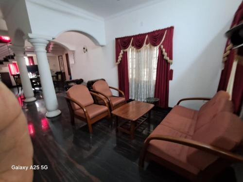 a waiting room with chairs and a table and a window at 3 BHK House in Trichūr