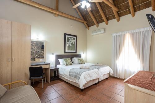 a bedroom with a bed and a desk and a bed sidx sidx sidx at Stonebreaker Country Lodge in Oudtshoorn