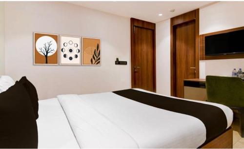 a bedroom with a white bed and a kitchen at Townhouse Oak Salt Lake Kolkata Formerly SLS Tower in Thākurdwari
