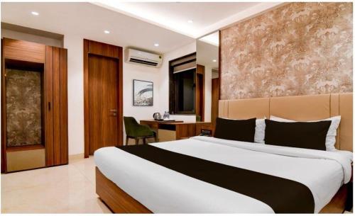 a bedroom with a large bed and a desk at Townhouse Oak Salt Lake Kolkata Formerly SLS Tower in Thākurdwari