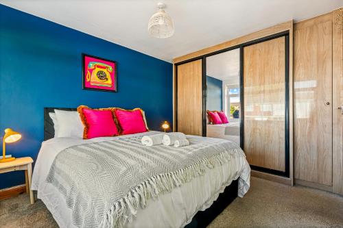 a blue bedroom with a large bed with pink pillows at Spacious 4 Bed House in Exhall, Sleeps 7 in Exhall