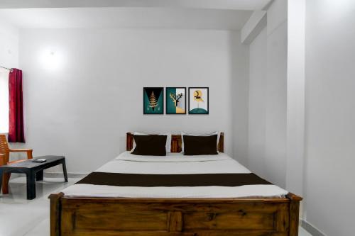 a bedroom with a wooden bed in a white room at Hotel O Shree Guest House in Khandagiri