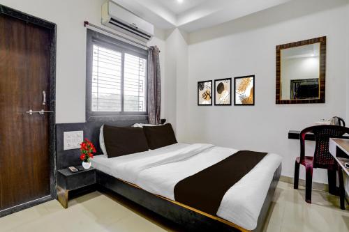 シルディにあるHotel O Sai Teerth Theme Park Formerly Sai Dhanlaxmiのベッドと机と鏡のある寝室