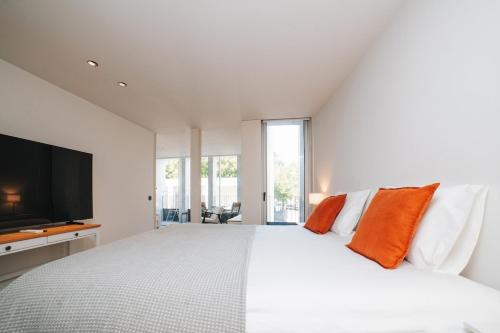 a white bedroom with a large bed with orange pillows at Apartment Oro in Braga