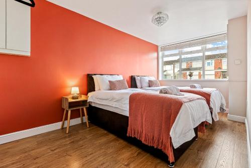 a bedroom with an orange accent wall and a bed at Spacious 4 Bed House in Exhall, Sleeps 7 in Exhall