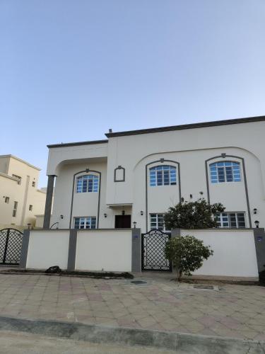 un bâtiment blanc avec des fenêtres et une clôture dans l'établissement Spacious 4-Bedroom Villa near Azaiba Beach, Muscat, à Mascate