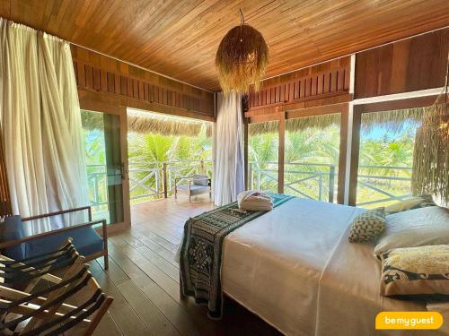 a bedroom with a large bed and large windows at Vila Pukara - Moitas in Praia de Moitas