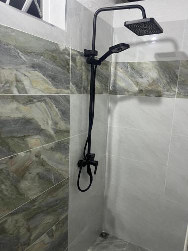 a shower with a black shower head in a bathroom at Kreolia Blue-Waters in Trou d'Eau Douce