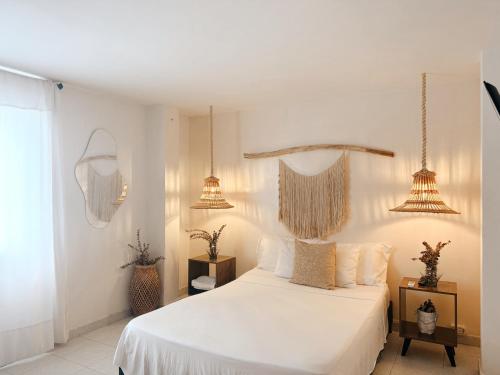 1 dormitorio con 1 cama blanca y 2 luces colgantes en Apartamento centro a una cuadra de la playa y parque de los novios, en Santa Marta