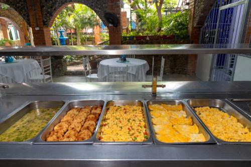 a buffet line with trays of food on it at Hotel Playa Salguero By GEH Suites in Santa Marta