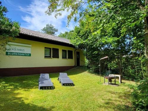 a building with benches in the grass in front of it at Haus Blumengarten in Thalfang