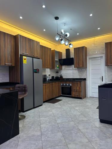 a kitchen with a stainless steel refrigerator and wooden cabinets at Cozy 4 bedroom at community 18 near spintex in Spintex