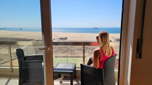 a woman sitting on a balcony looking out at the ocean at Bella Vista - Vue Océan in Buarcos