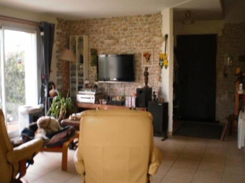 un soggiorno con un divano giallo e una TV di Les chambres de Florence a Saint-Jouan-de-lʼIsle