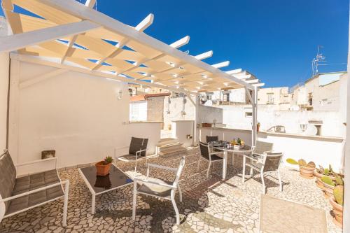 Un patio con sillas y mesas y una pérgola. en Casa Oasi del Mare, en Gallipoli