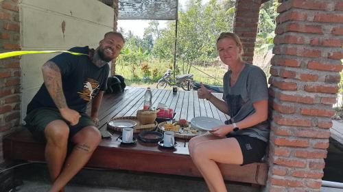 a man and a woman sitting next to a table with food at Lentera Lombok in Tetebatu