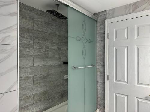 a shower with a glass door in a bathroom at Beautiful 3 BR Near Town & Beach w King Bed in Patchogue