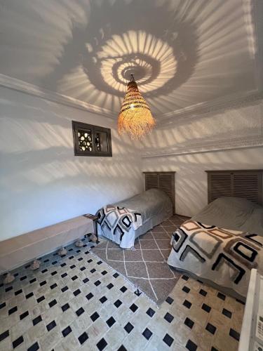 a bedroom with two beds and a ceiling with a chandelier at Traditional Aicha House in Tozeur