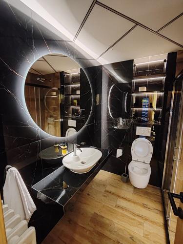 a bathroom with a sink and a toilet and a mirror at Princ lux spa with sauna and jacuzzi in Novi Sad