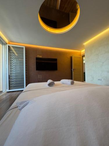 a bedroom with a large white bed with a large chandelier at Princ lux spa with sauna and jacuzzi in Novi Sad
